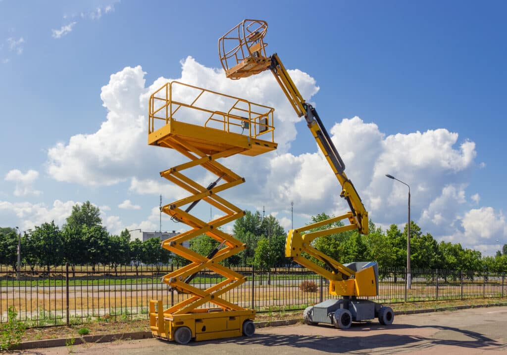 Yellow self propelled articulated boom lift and scissor lift on background of street with trees and sky. Alta equipment sales revenue up 45% YoY.