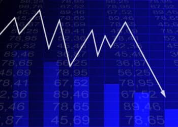 Arrow graph going down and electronic stock numbers on a blue background.