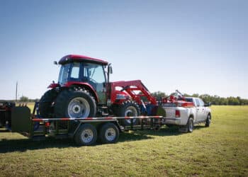 Texas farming: delivering/towing a large red tractor.