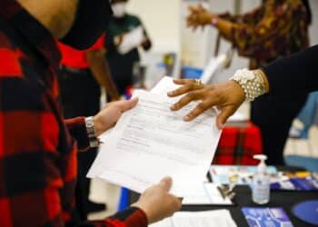 A job seeker receives information from a recruiter during a Miami-Dade County job fair in Miami, Florida, U.S., on Thursday, Dec. 16, 2021. Applications for U.S. state unemployment benefits rose last week but remained near the lowest levels of the pandemic as the labor market recovery continues.