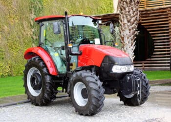 Red compact tractor on the ground in front of the building.