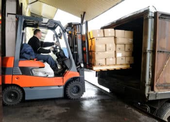 Electric forklift in warehouse loading cardboard boxes