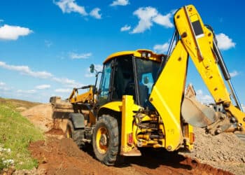 Wheel loader excavator with backhoe unloading sand at eathmoving works in construction site