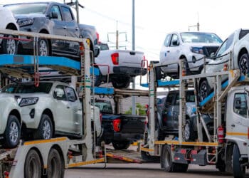 Car carrier trailer transport new car from manufacturing factory to dealer. auto vehicle haul truck delivery. transport logistics in automotive industry. car carrier trailer load new car to shipping.