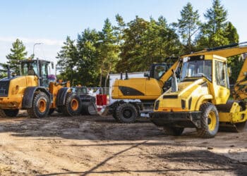 Many different heavy industrial machinery equipment at construction site parking area.