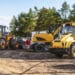 Many different heavy industrial machinery equipment at construction site parking area.