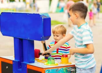 Children playing whack a mole arcade game at an amusement park.