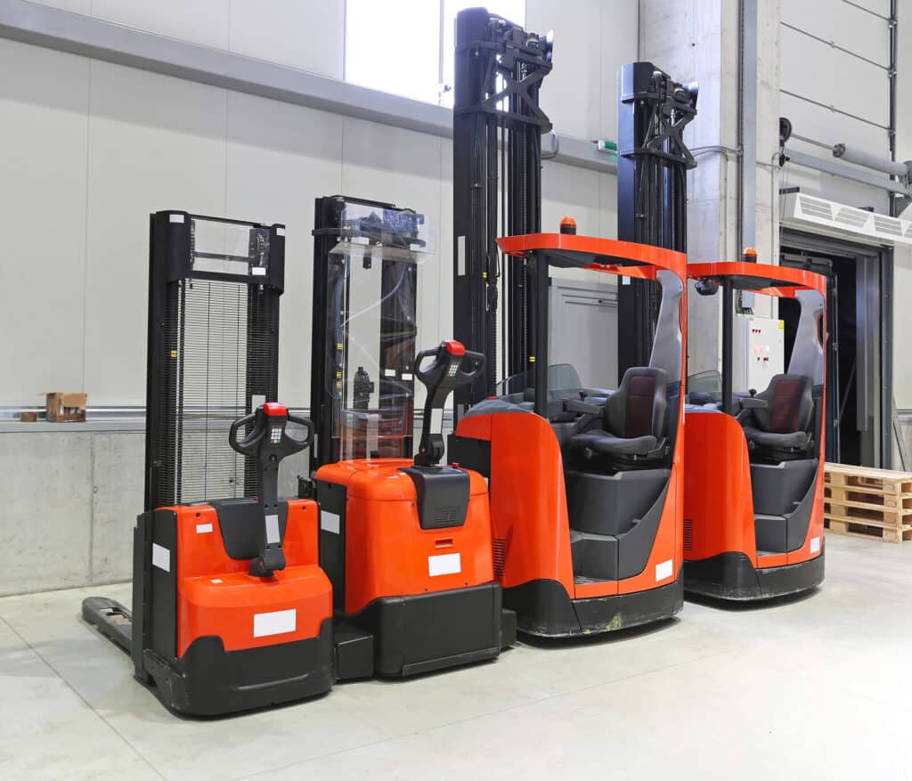 Four red forklift trucks in distribution warehouse