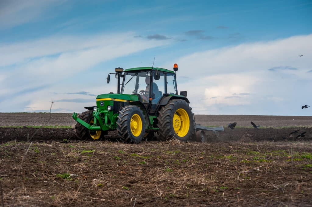 Baykivtsi, ternopil region, ukraine - april 20, 2021: a tractor 90s john deere 2850 with a homemade plow prepares the field for sowing