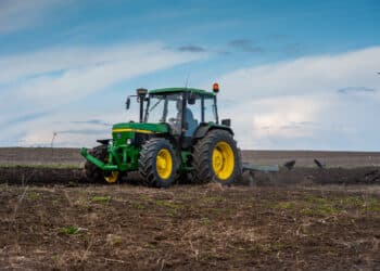 Baykivtsi, ternopil region, ukraine - april 20, 2021: a tractor 90s john deere 2850 with a homemade plow prepares the field for sowing
