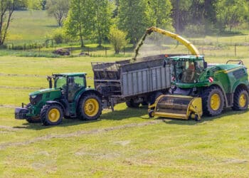 Kaplice, czech republic - 06 02 2021: self-propelled forage harvester and tractor with silage trailer in the field