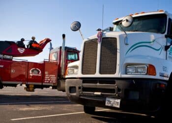 A tow truck sits next to an Arrow Trucking Co. tractor at the company's headquarters in Tulsa, Oklahoma, U.S., on Monday, Jan. 4, 2010. Arrow Trucking Co., the 61-year-old Tulsa-based flatbed carrier, suspended operations on Dec. 22, 2009, laying off employees and stranding scores of drivers by cancelling fuel credit cards, Tulsa World reported. Federal Authorities later issued an emergency order to executives to retrieve company trucks and trailers from truck stops and parking areas around the country.