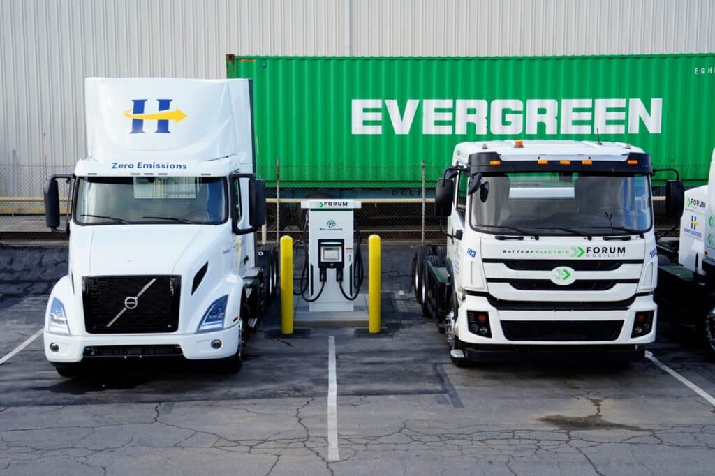 A Tellus Power EV charger between a Volvo VNR electric truck, left, and a second generation BYD 8TT electric semi truck at logistics hub in Long Beach, California. 