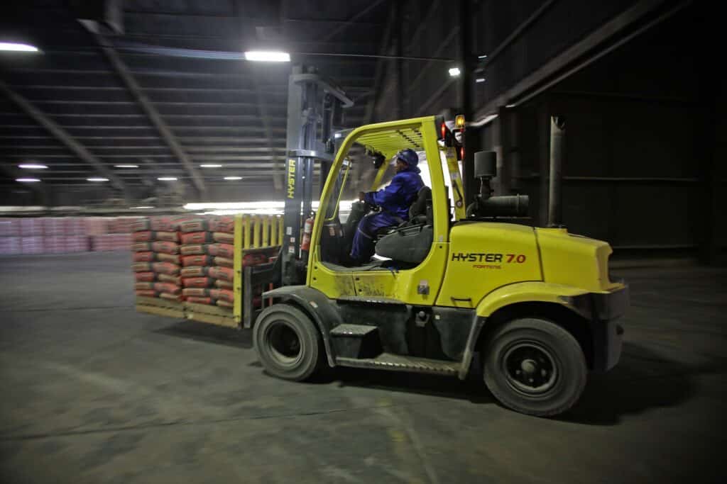 A worker uses a Hyster-Yale Materials Handling Inc. pallete truck to load bags of cement at the Hercules cement plant, operated by PPC Ltd., in Pretoria, South Africa, on Thursday, Sept. 3, 2015. PPC Ltd., South Africa's largest cement maker, has drawn up a plan to generate 400 million rand ($34 million) in extra profit each year as the company seeks to improve performance amid a flagging share price.