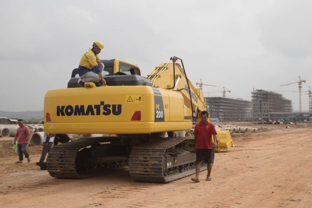 A worker squats on a Komatsu Ltd. excavator near the construction site for the Otres 2 development in Sihanoukville, Cambodia, on Saturday, March 31, 2018. It's against the law for Cambodians to gamble. Yet in Sihanoukville, a once-sleepy resort town where three dozen casinos have sprung up, most in the past two years, Cambodians are betting that an infusion of Chinese-built infrastructure will pay off with jobs and prosperity