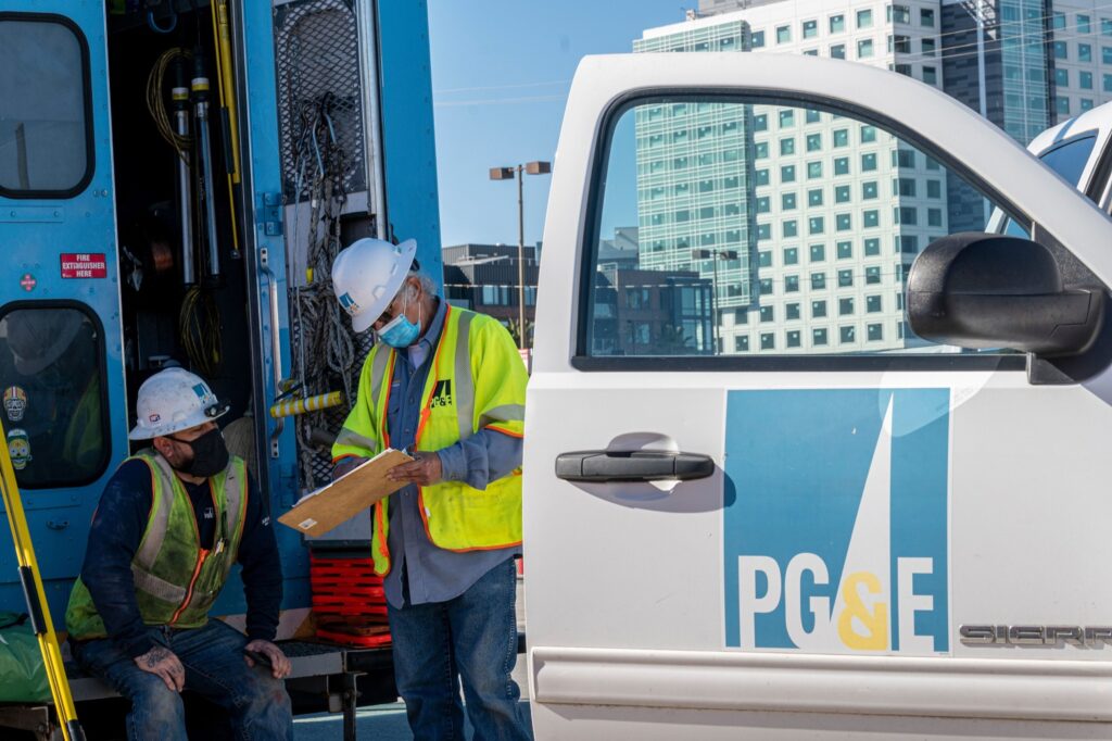 Pacific Gas & Electric Corp. (PG&E) workers wearing protective masks look at clipboard in San Francisco, California, U.S., on Wednesday, Feb. 24, 2021. PG&E Corp. is scheduled to release earnings figures on February 25.