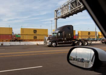 Trucks enter the Port of Los Angeles in Los Angeles, California, U.S., on Tuesday, Nov. 16, 2021. The historic traffic jam at the Port of Los Angeles has eased slightly as ocean carriers face fines for letting cargo linger and sweeper ships arrive to haul off empty containers.