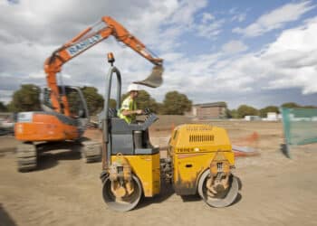 A builder drives a Terex Corp. ride-on roller past an excavator during house construction at Persimmon Plc's St. Andrew's Park residential housing development in the Uxbridge district of London, U.K., on Monday, Aug. 18, 2014. Persimmon, the U.K.'s largest homebuilder by market value, said sales of houses and apartments rose 28 percent in the first half as demand from buyers increased.