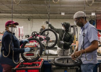 Employees with Bicycle Corporation Of America, a division of Kent International, Inc. work an assembly line at the company's manufacturing warehouse in Manning, South Carolina, U.S., on Thursday, May 13, 2021.