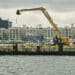 A crane sits on a pier in the IndUS,try City neighborhood of Brooklyn, New York, US, on Thursday, July 17, 2025. The crew of an American-flagged barge will lay cable to connect the Empire Wind farm to New York Citys grid  a milestone for an embattled sector.