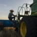 A farmer and his dog climb into a combine to harvest wheat in Corn, Oklahoma.