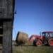A farmer operates a tractor to transport a bale of hay at a farm in Pleasureville, Kentucky.